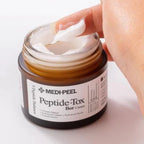 MEDI-PEEL Peptide-Tox Bar Cream jar with a hand applying cream on a white background